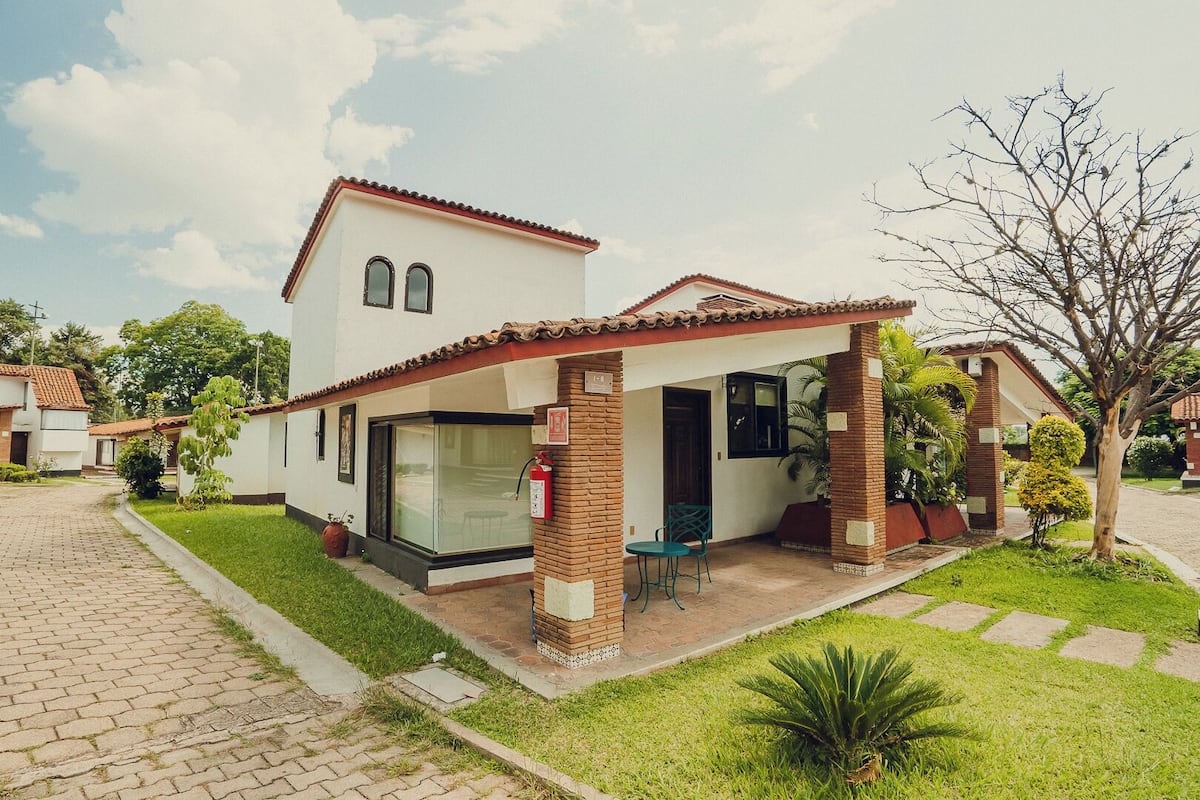 A modern two-story house with a patio, a glass door entrance, and a brick column.