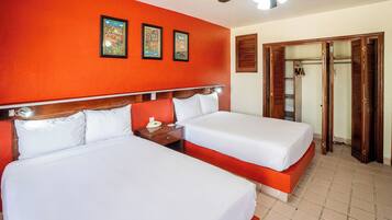 A hotel room with two beds, a wooden headboard, a ceiling fan, and a wardrobe with a mirror.