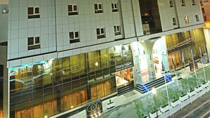 A multi-story hotel with a modern facade, large windows, and a prominent entrance with steps. - Corp Executive Hotel Doha Suites (Doha)