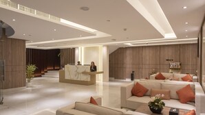 A modern hotel lobby with a reception desk, seating area, and a staircase leading to upper floors. - Corp Executive Hotel Doha Suites (Doha)
