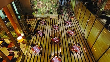 A rooftop dining area with tables and chairs arranged in a grid pattern, overlooking a cityscape.