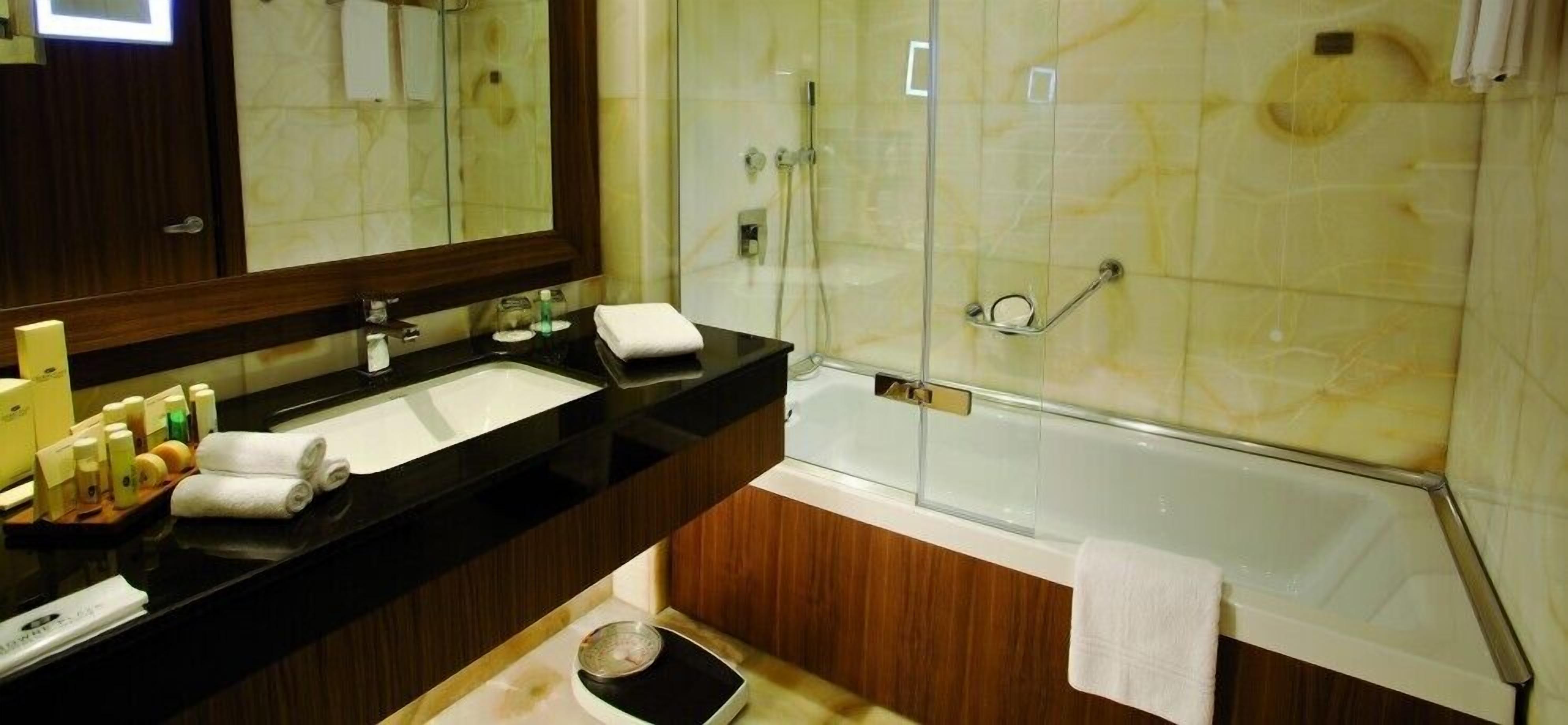 A bathroom with a sink, mirror, and shower.