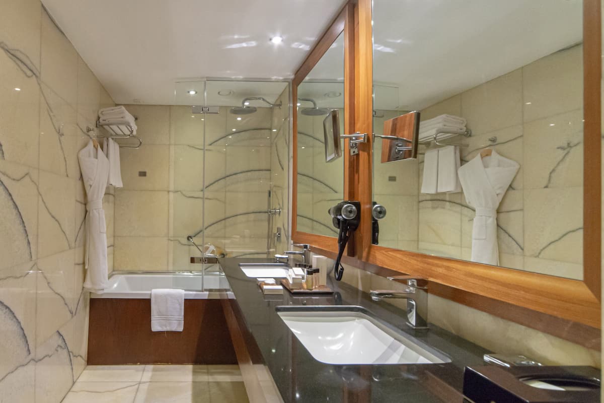 A modern bathroom with two sinks, a large mirror, and a glass-enclosed shower.