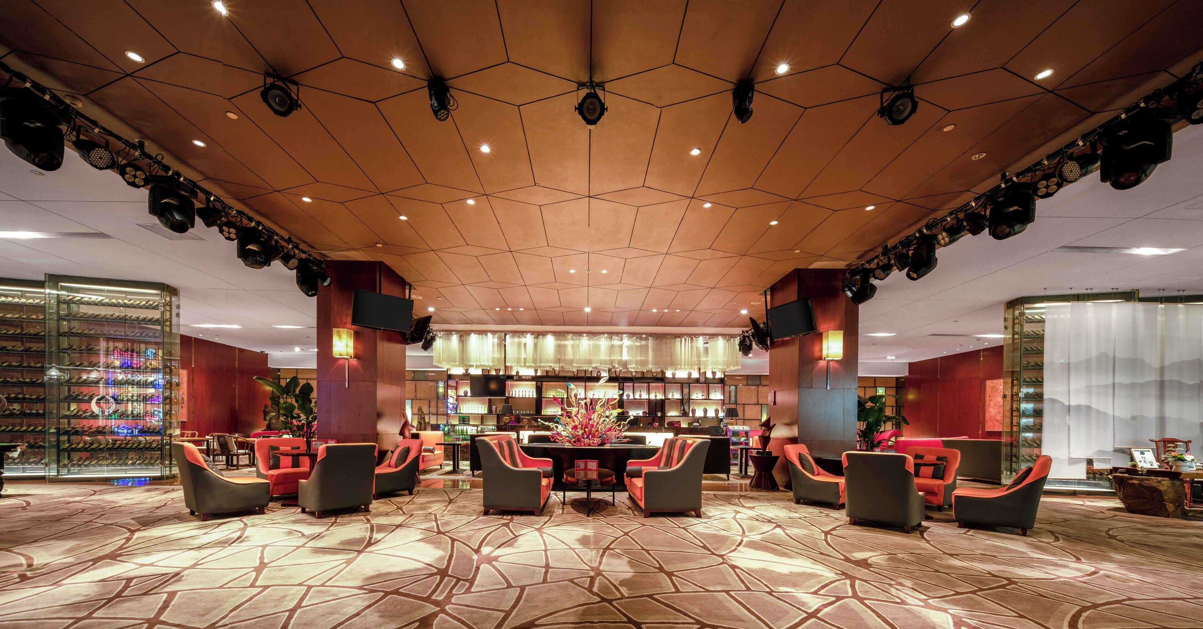 A spacious lobby with a hexagonal ceiling, multiple seating areas, and a bar.