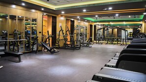 Un gimnasio con equipos de ejercicio variados, espejos y una cinta de correr T7X.