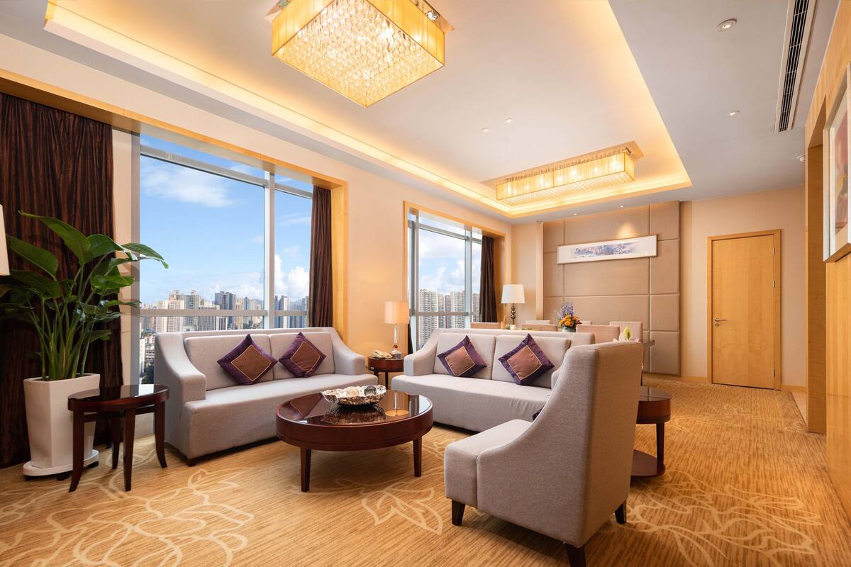 A spacious hotel lobby with two sofas, a coffee table, and a large potted plant.