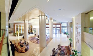 A spacious lobby with high ceilings, large columns, and a central seating area. - Crowne Plaza Xiangyang by IHG (Xiangyang)