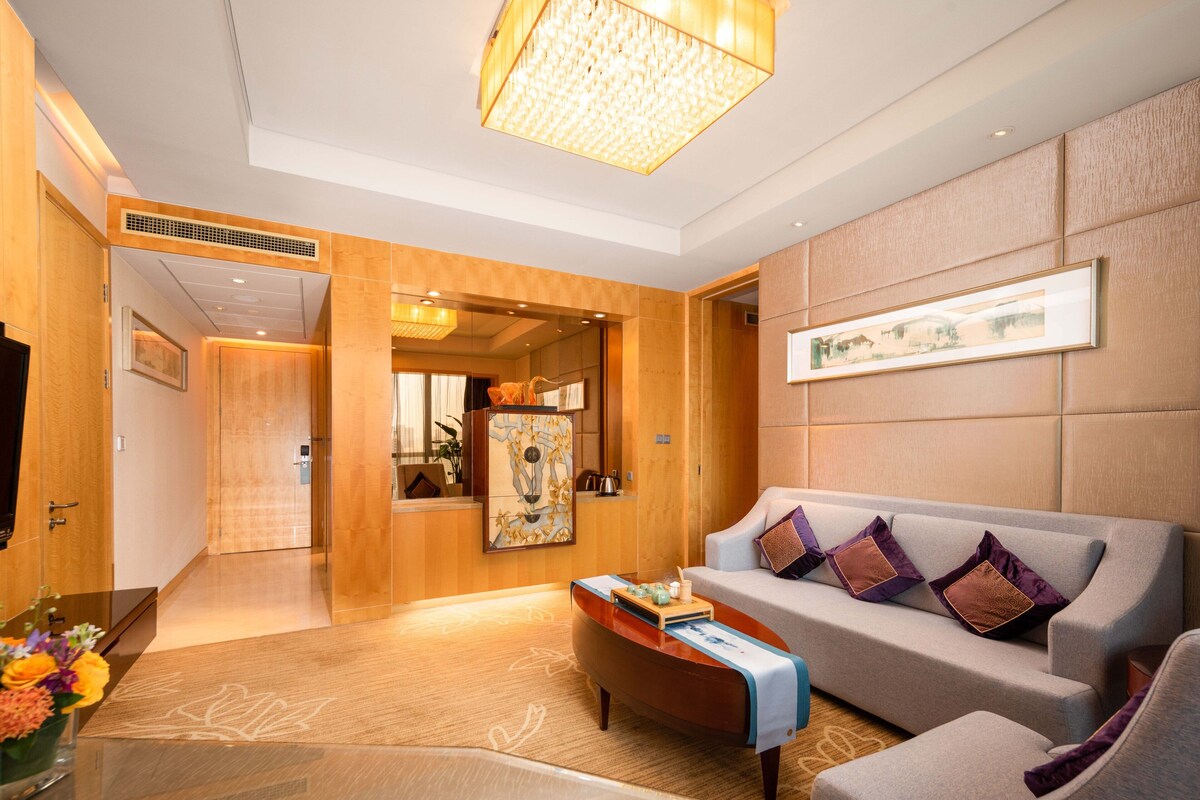 A modern hotel lobby with a sofa, a coffee table, and a chandelier.