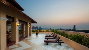 A rooftop terrace with lounge chairs and a dining area, overlooking a city skyline. - Aiyara Palace (Pattaya)