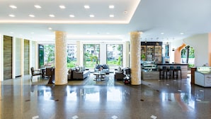A spacious lobby with a polished floor, seating area, and a bar. - Aiyara Palace (Pattaya)
