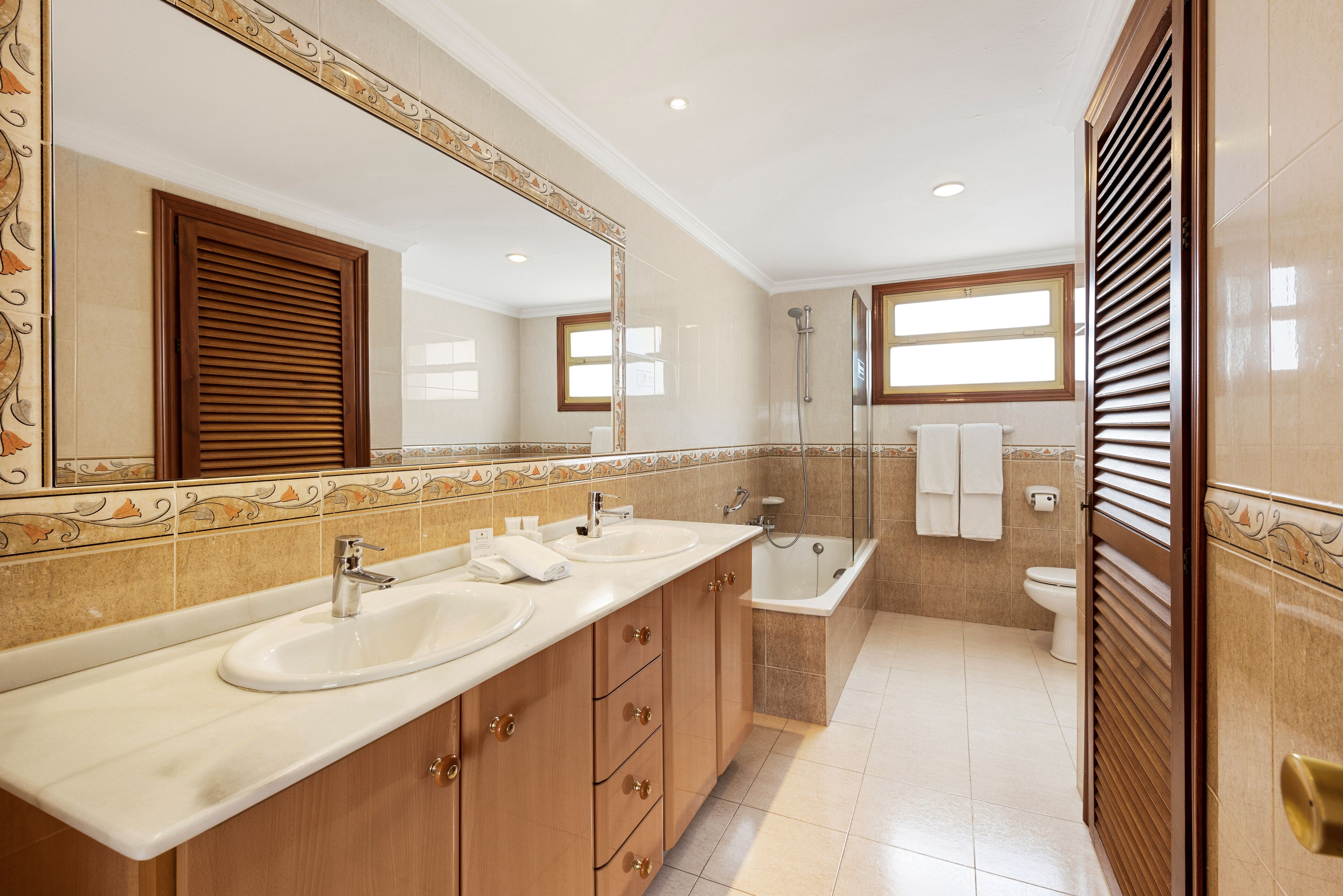 A bathroom with two sinks, a bathtub, and a toilet.
