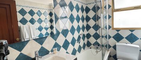 A bathroom with a sink, bathtub, and toilet, featuring blue and white diamond-patterned tiles.