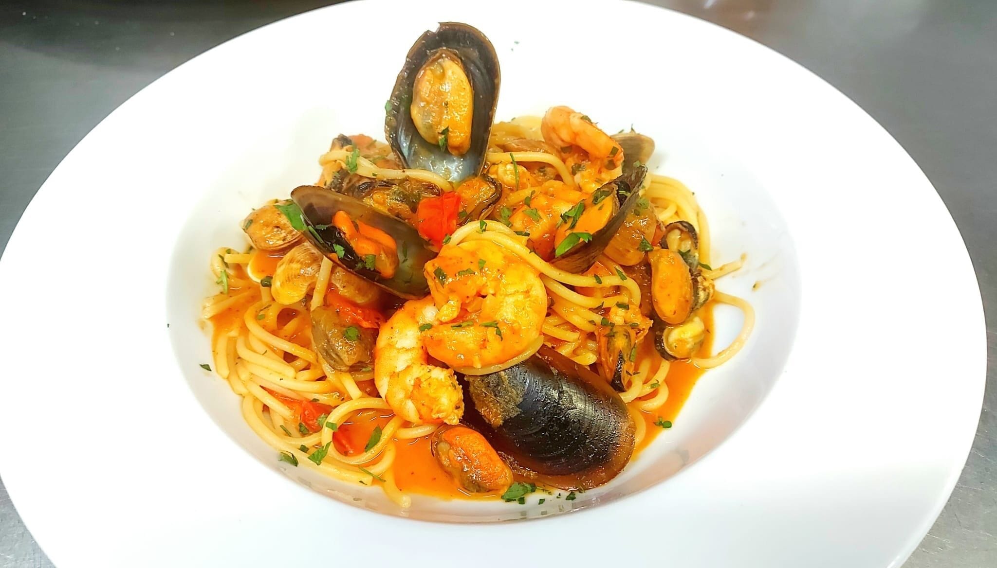 A plate of seafood pasta with mussels and shrimp.