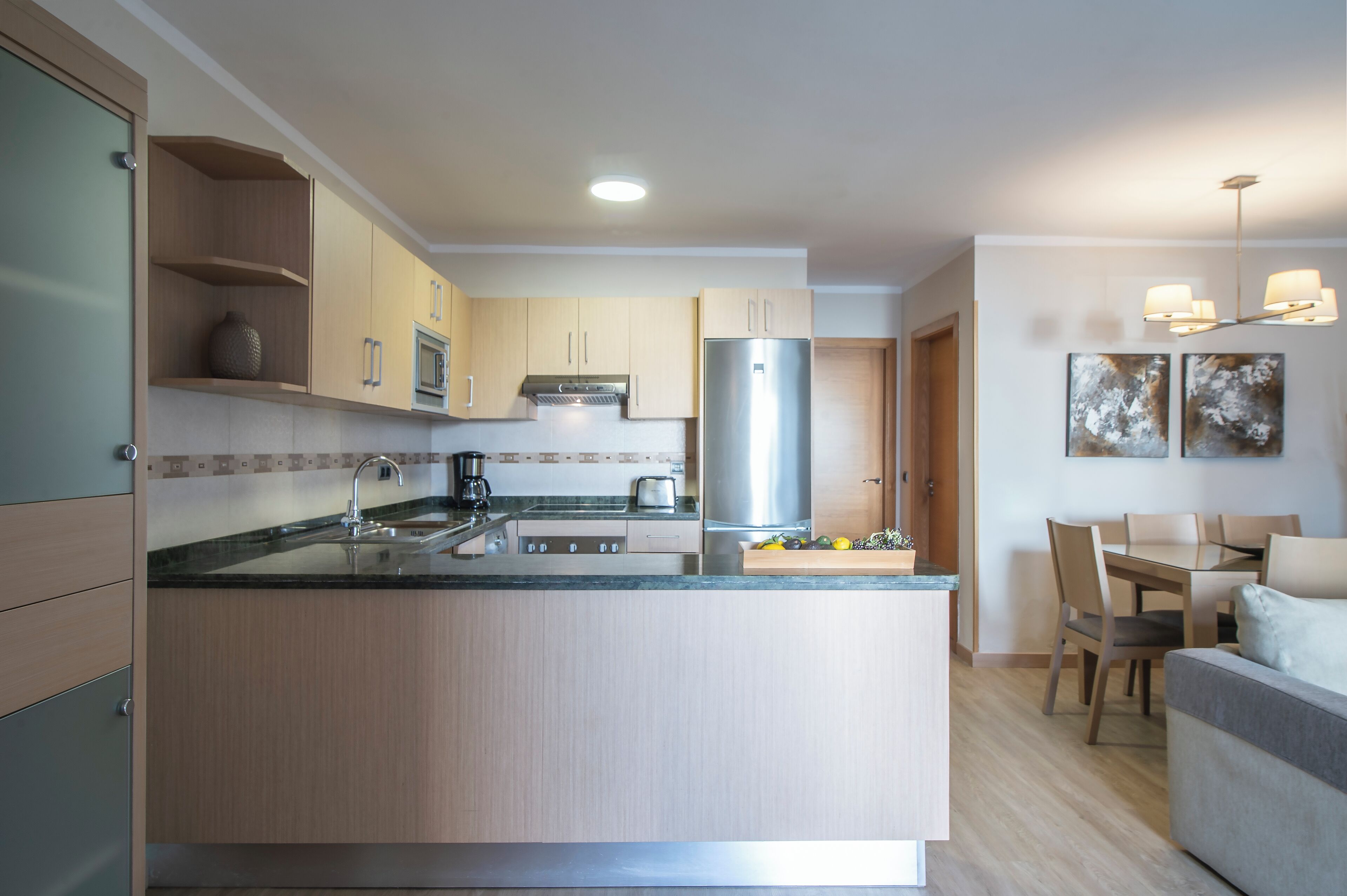 A modern kitchen with a central island, stainless steel appliances, and a dining area with a table and chairs.