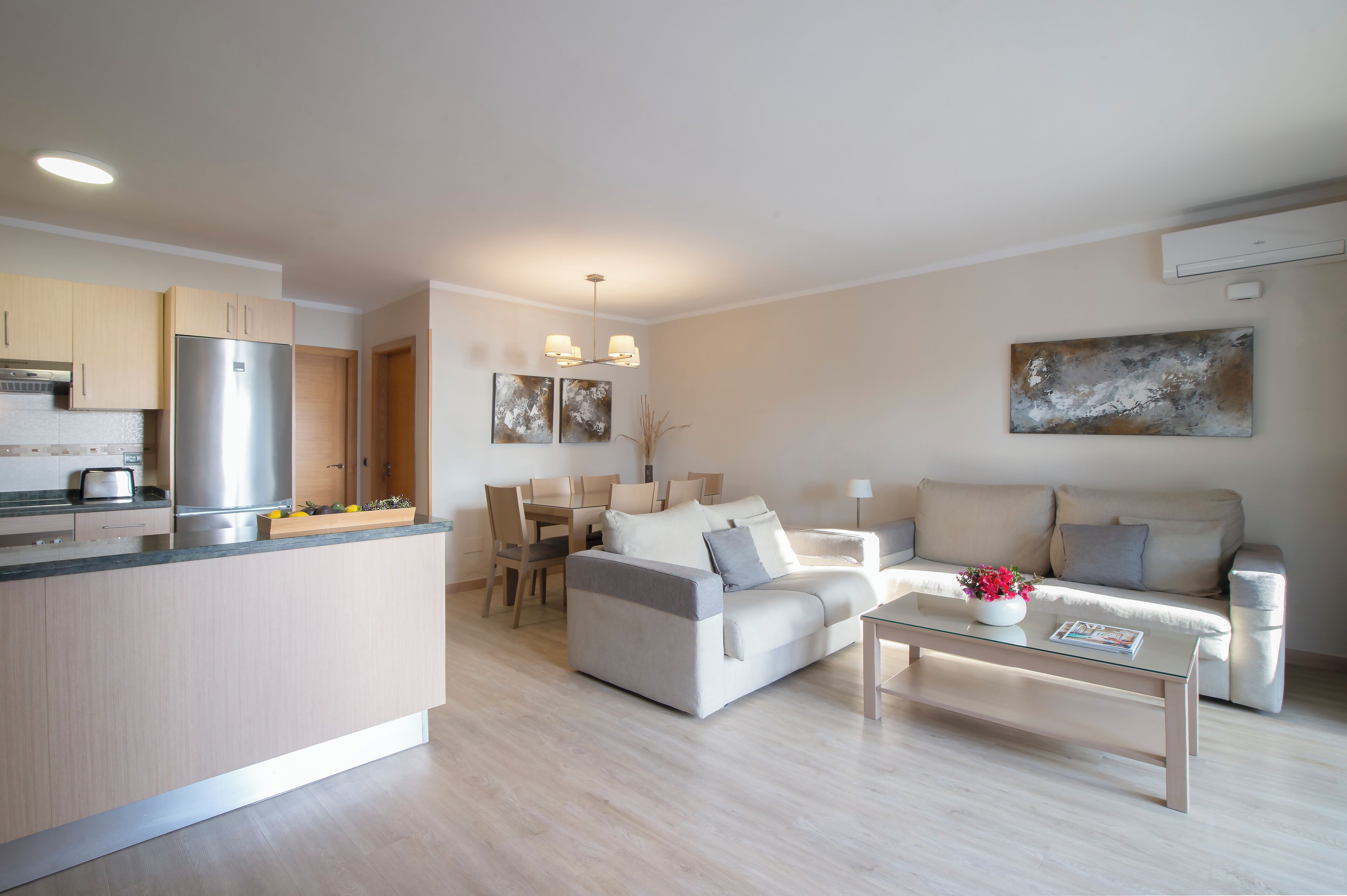Ein modernes Wohnzimmer mit einer Couch, einem Couchtisch und einem Essbereich mit Stühlen und einem Tisch.