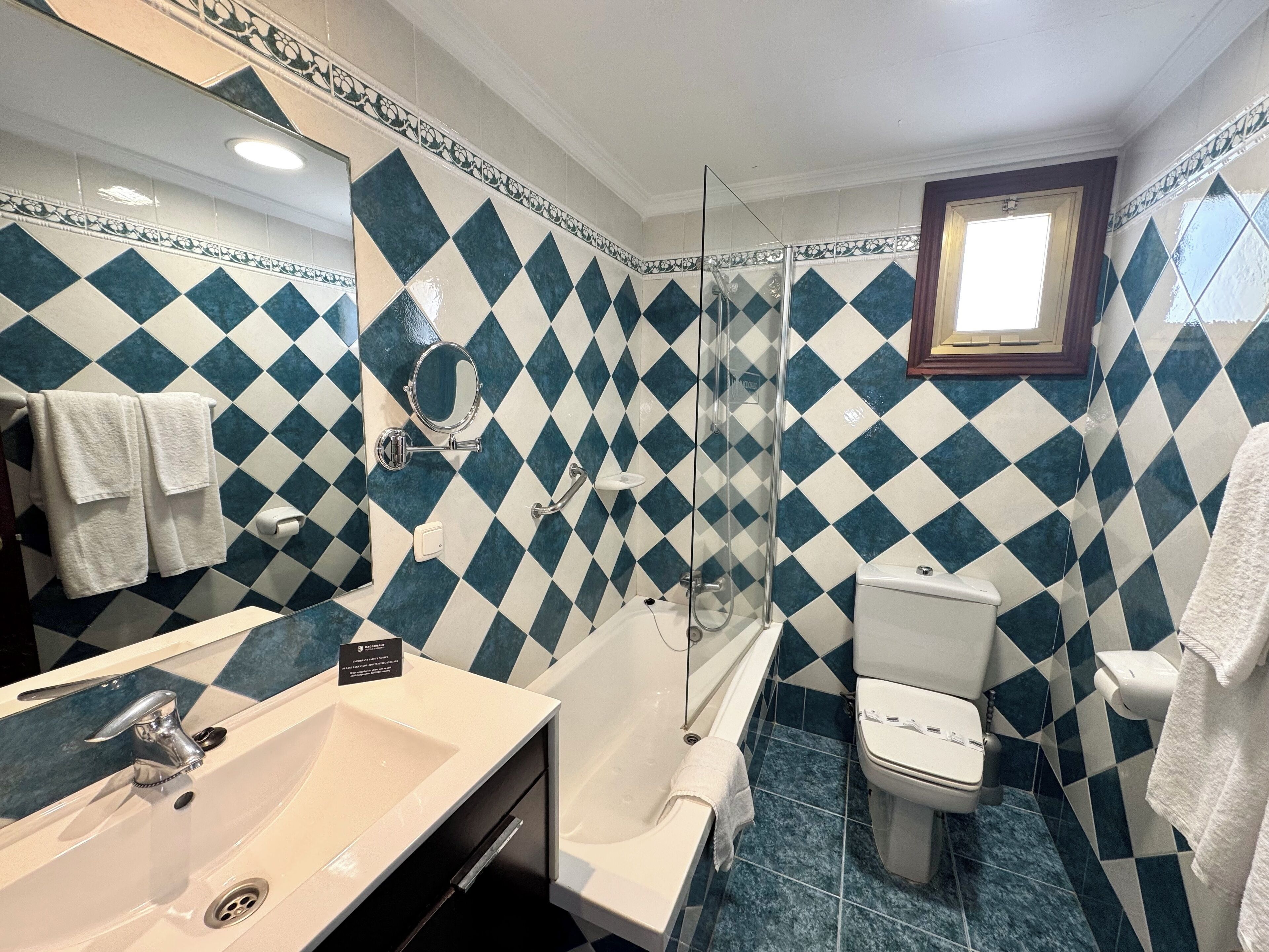 Une salle de bain avec un lavabo blanc, une douche fermée par des parois en verre et des toilettes.