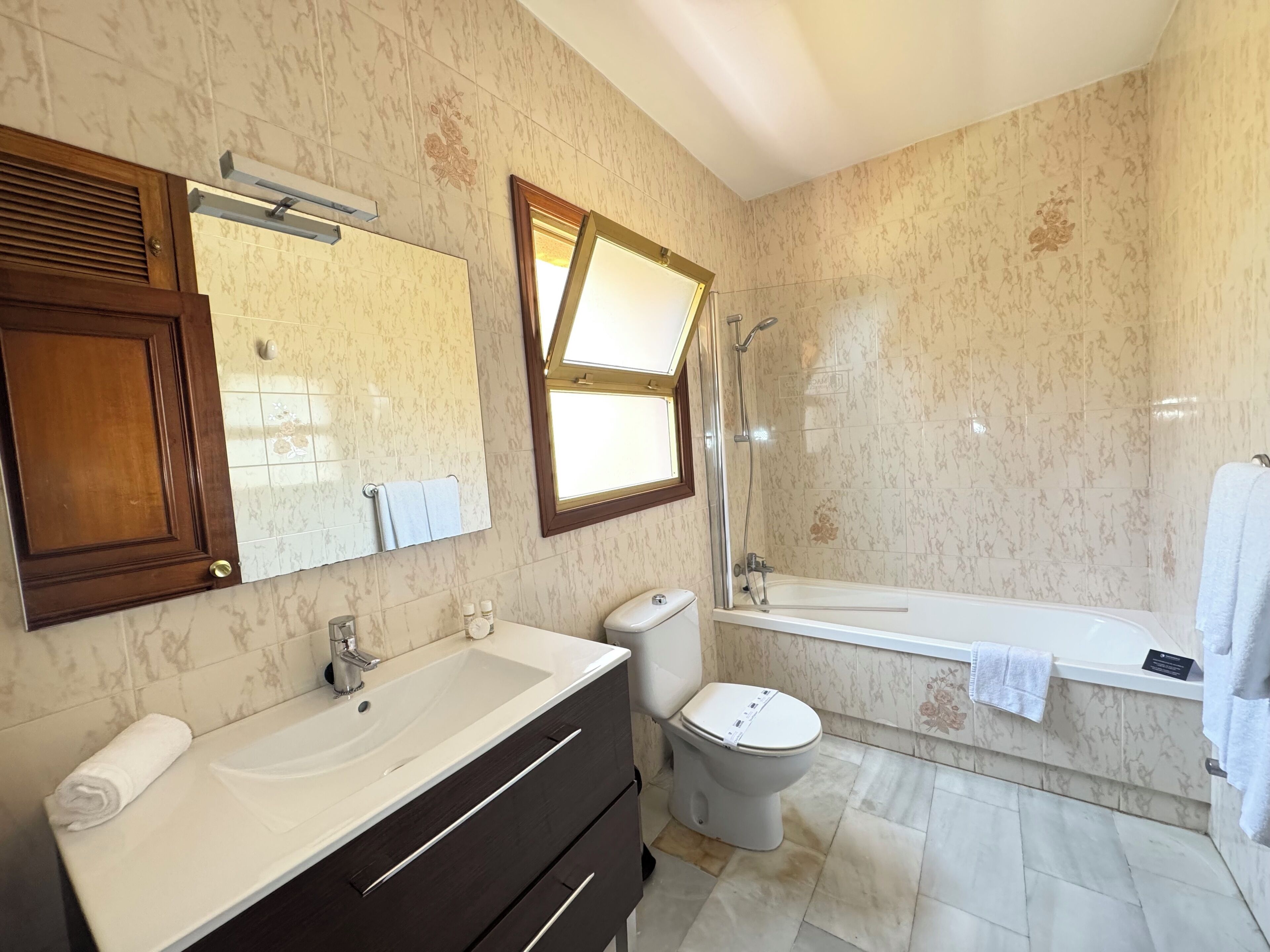 A bathroom with a sink, vanity, toilet, and a shower area.