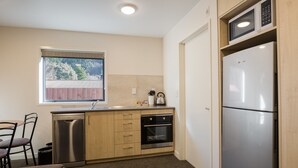A compact kitchen with a dishwasher, oven, and microwave. - Bella Vista Queenstown (Queenstown)