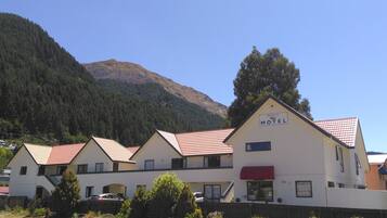 A row of white buildings with red roofs, labeled as a motel, with a mountain in the background.