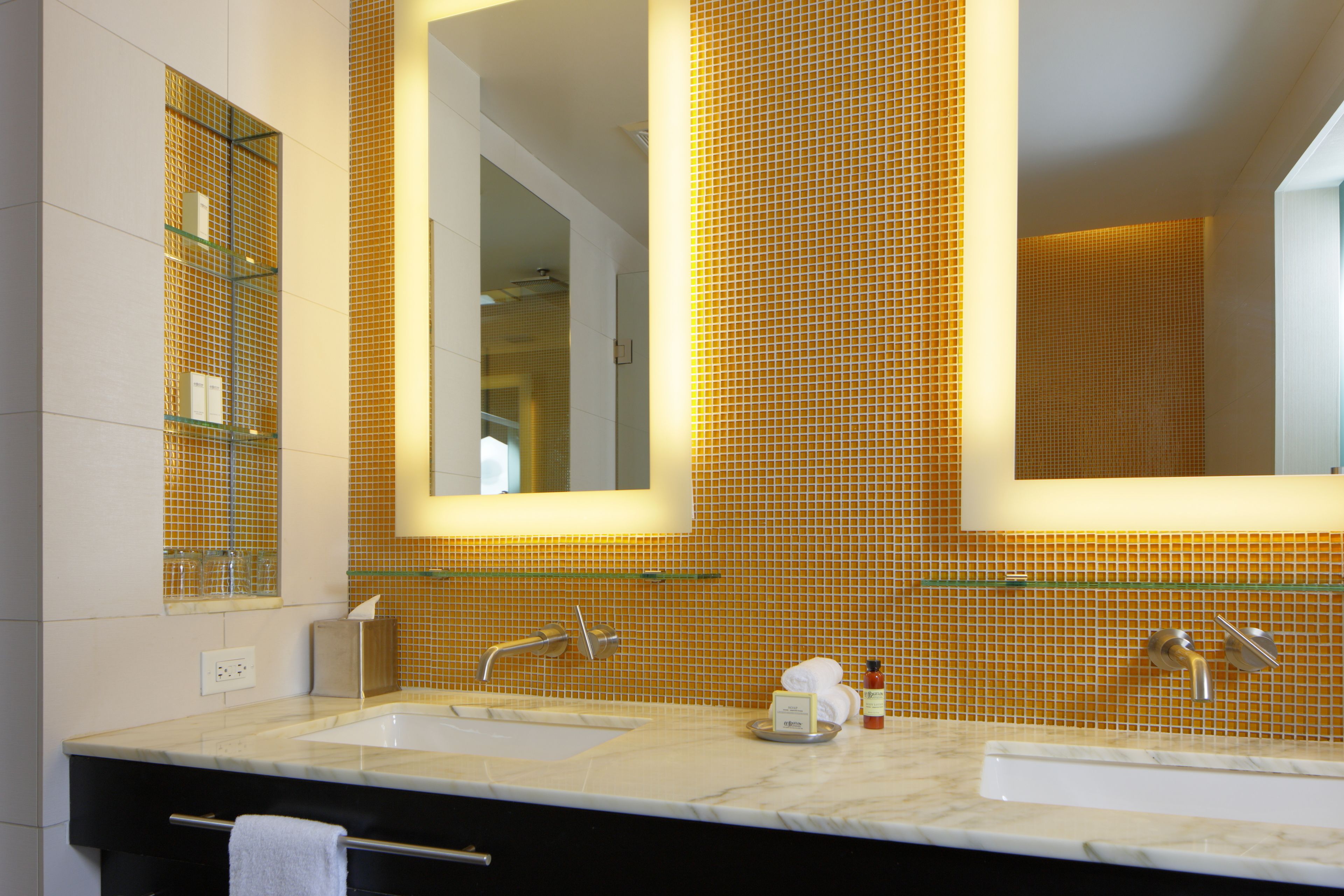 A bathroom with two sinks, a large mirror, and a tiled wall.