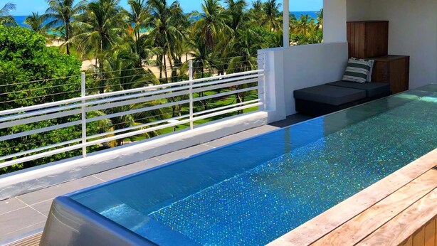 Una piscina a sfioro moderna con vista sull'oceano e palme.