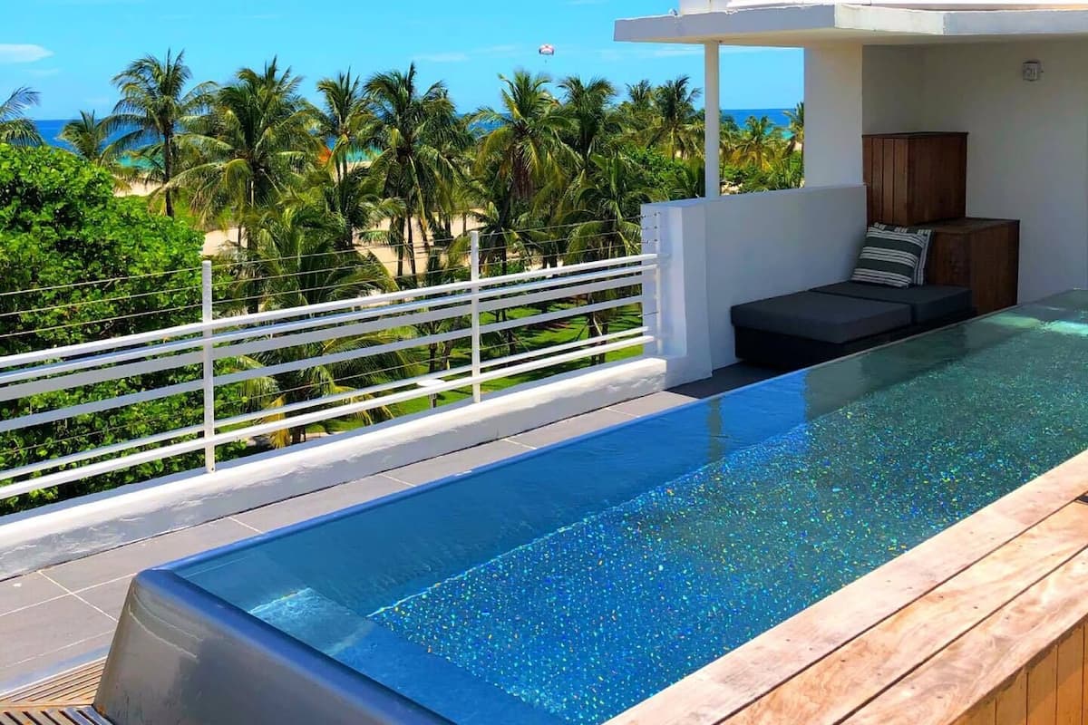 A modern infinity pool with a clear view of the ocean and palm trees.