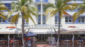 Un ristorante sulla spiaggia con posti a sedere all'aperto e palme.