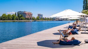A wooden pier with lounge chairs and umbrellas overlooking a calm body of water. - Hotel Kyriad Vichy Spa Cinq Mondes (Vichy)