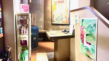 A reception area with a counter, a shelf with various items, and a poster on the wall.