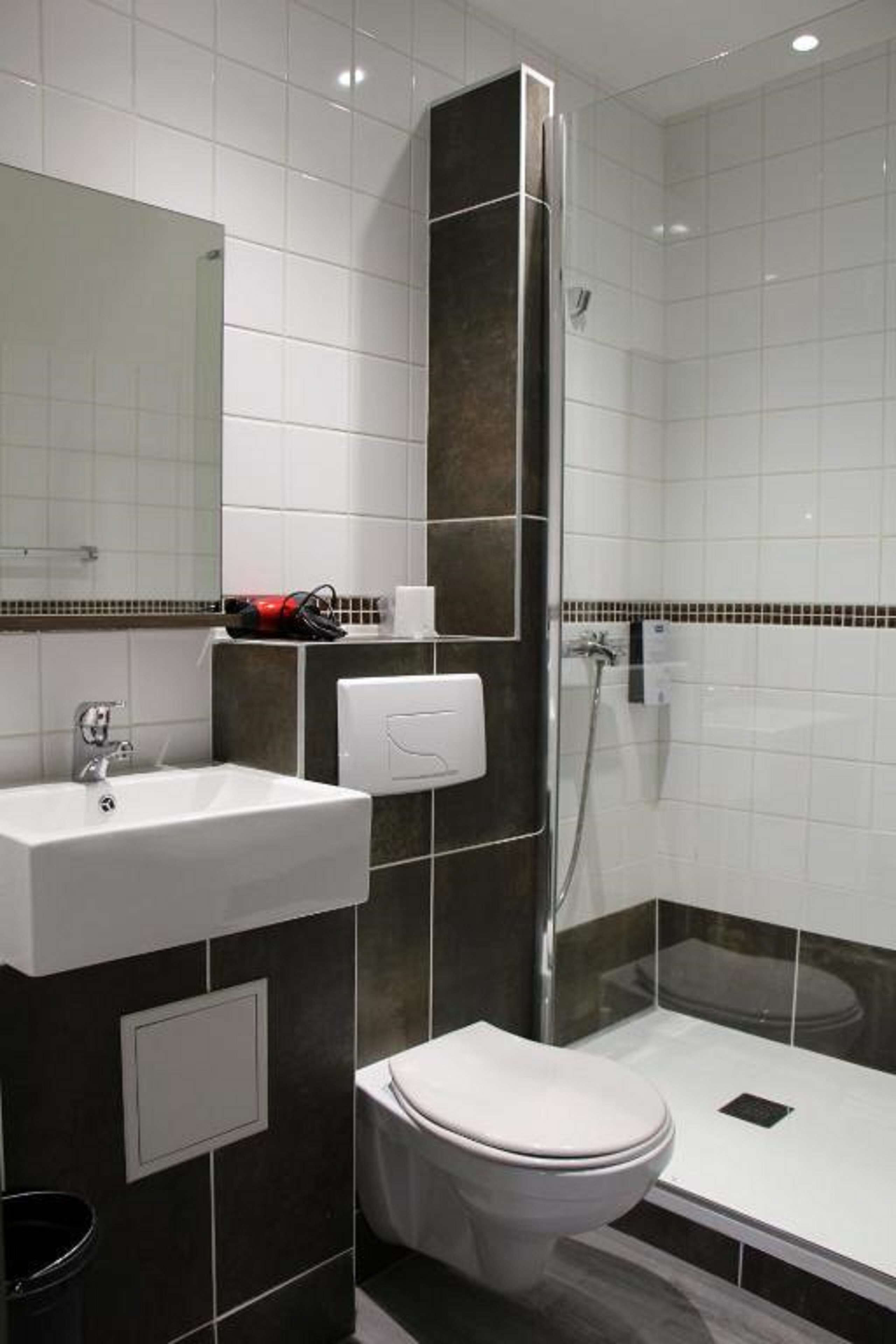 A modern bathroom with a white sink, a toilet, and a glass-enclosed shower.