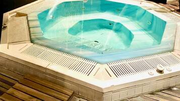 Un jacuzzi de forma rectangular, rodeado por un suelo de baldosas con un borde de madera.