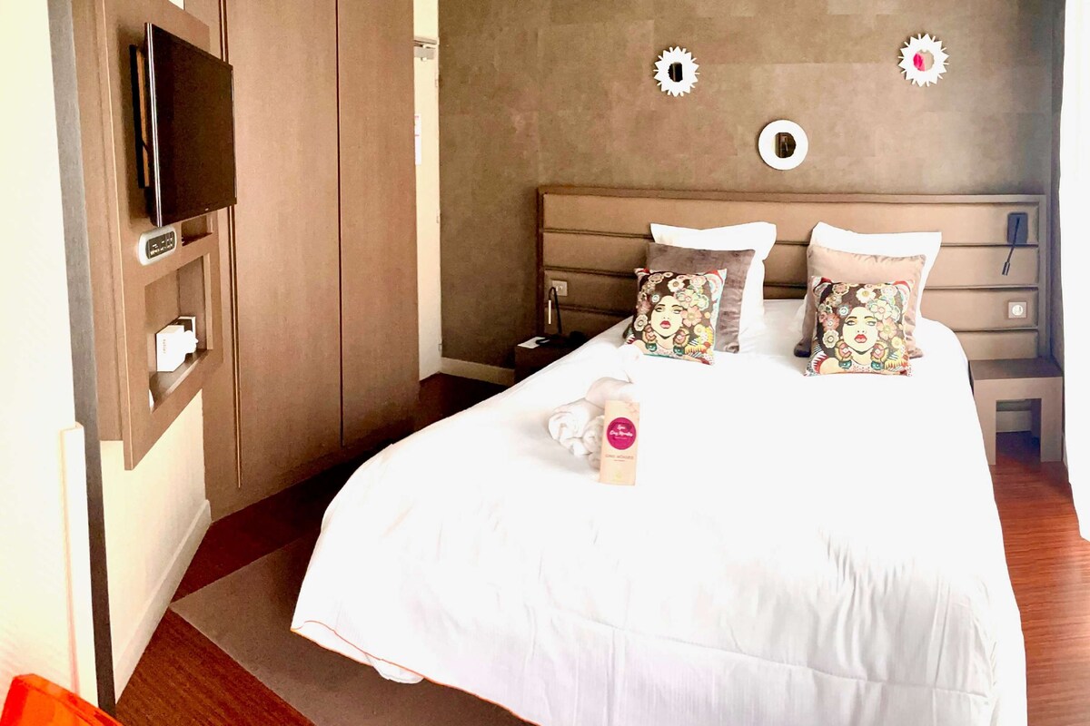 Habitación de hotel con cama, televisor, escritorio y pared decorada.