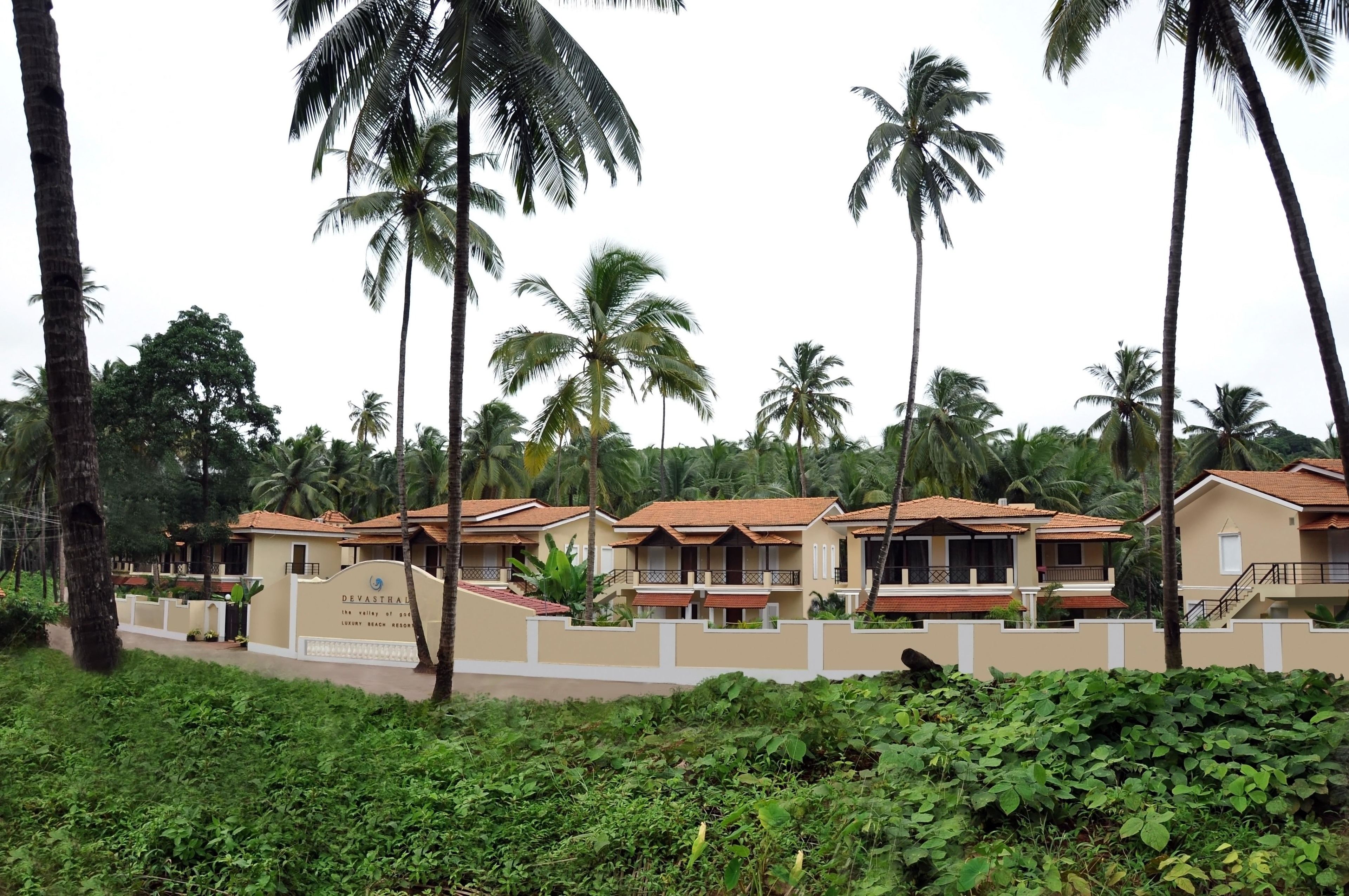 A resort with multiple bungalow-style buildings, surrounded by lush greenery and palm trees.