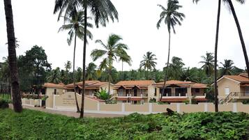A resort with multiple bungalow-style buildings, surrounded by lush greenery and palm trees.