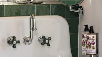 Ein Badezimmer mit einem weißen Waschbecken, grünen Fliesen, einem Spiegel und zwei Flaschen Körperlotion.