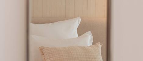 A bedroom with a bed, pillows, and three framed pictures on the wall.