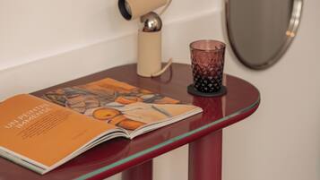 A magazine on a glass table with a candle holder beside it.