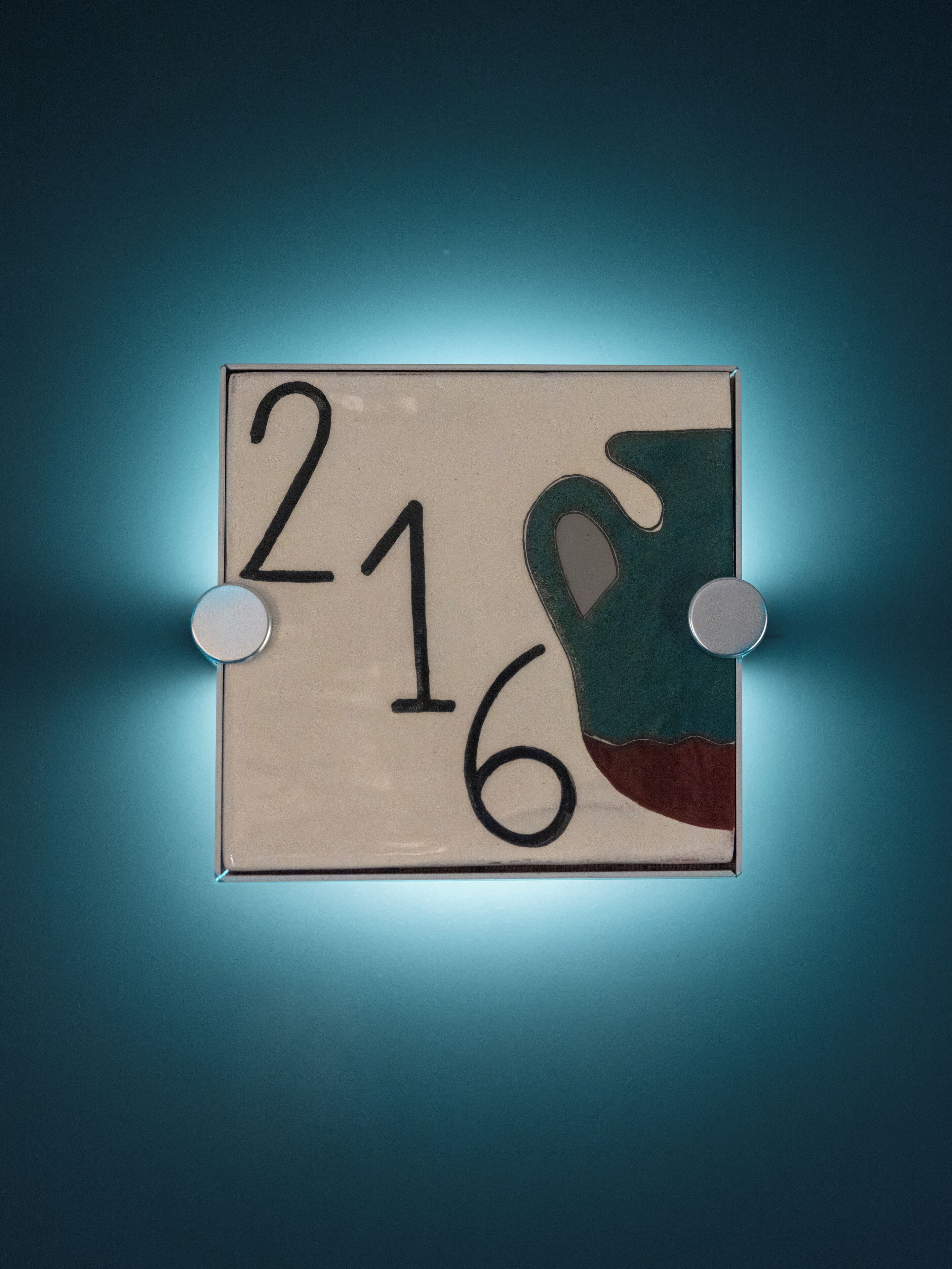 A wall-mounted sign with the numbers 216, featuring a cut-out shape of a hand.
