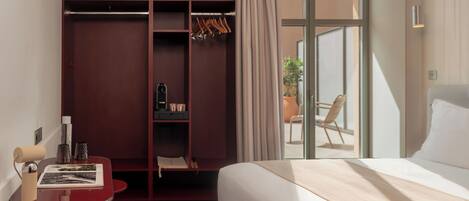 Hotelkamer met een bed, een bureau met stoel, een kledingkast en een schuifdeur naar een balkon.