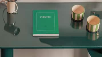 A green table with a book titled 'L'ODYSSEE' and two striped cups.