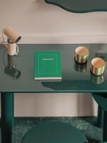 Un tavolo verde con un libro intitolato 'L'ODYSSEE' e due tazze a righe.