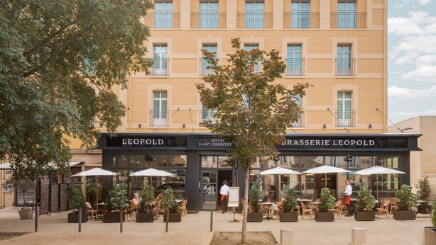 Un hotel con mesas al aire libre y un letrero que dice "LEOPOLD HOTEL SAINT CHRISTOPHE BRASSERIE LEOPOLD".