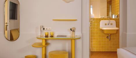 A hotel bathroom with a yellow sink, mirror, and vanity.
