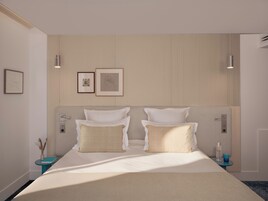 A modern hotel room with a large bed, two bedside tables, a wall-mounted light fixture, and framed artwork.