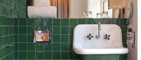 Une salle de bain avec des carreaux verts, un lavabo blanc et des toilettes.