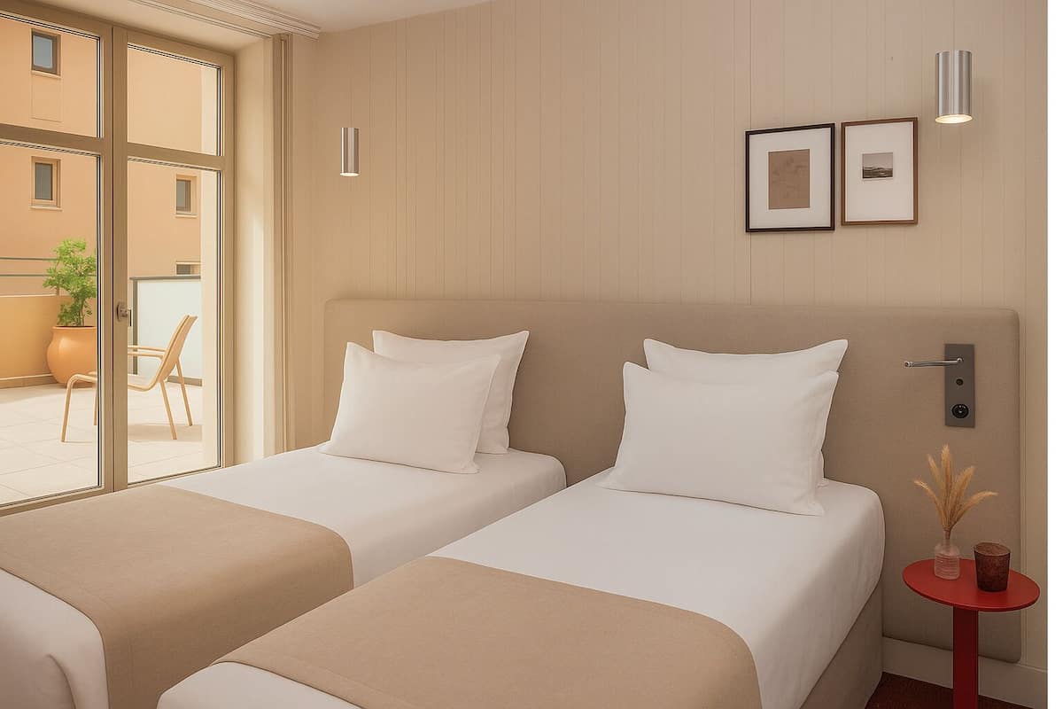 A hotel room with two beds, a small table with a vase, and a window with a view of the outside.