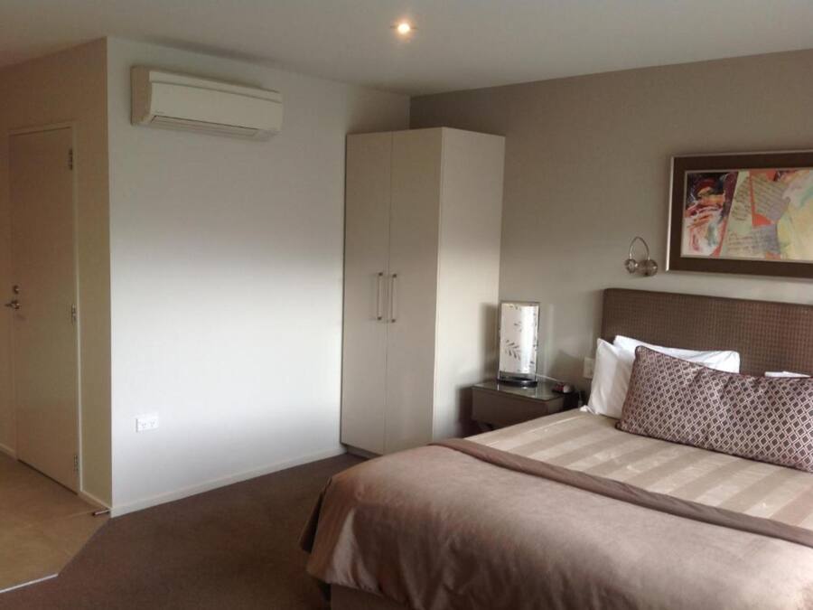 Een slaapkamer met een bed, een kledingkast, een nachtkastje en een airconditioning.