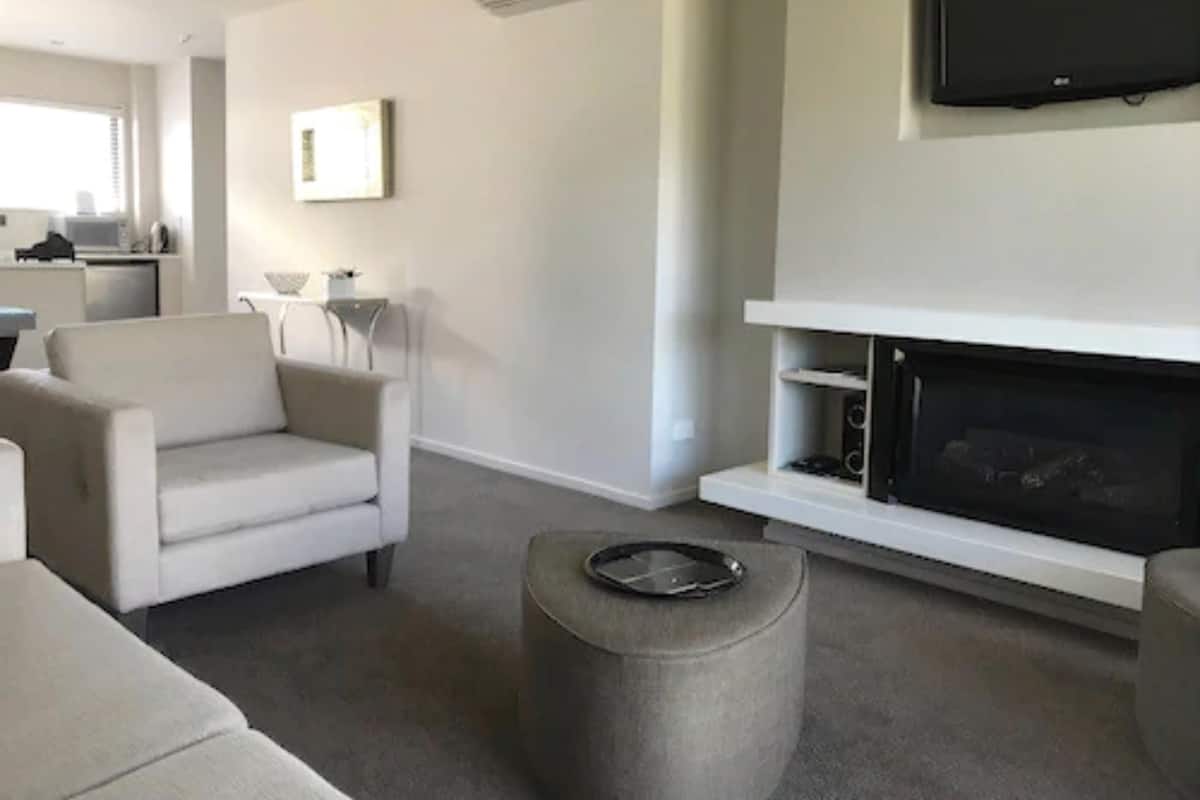 A modern living room with a fireplace, a flat-screen TV mounted above it, and a sofa.