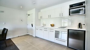 A modern kitchen with white cabinets, a built-in microwave, a dishwasher, and a refrigerator.