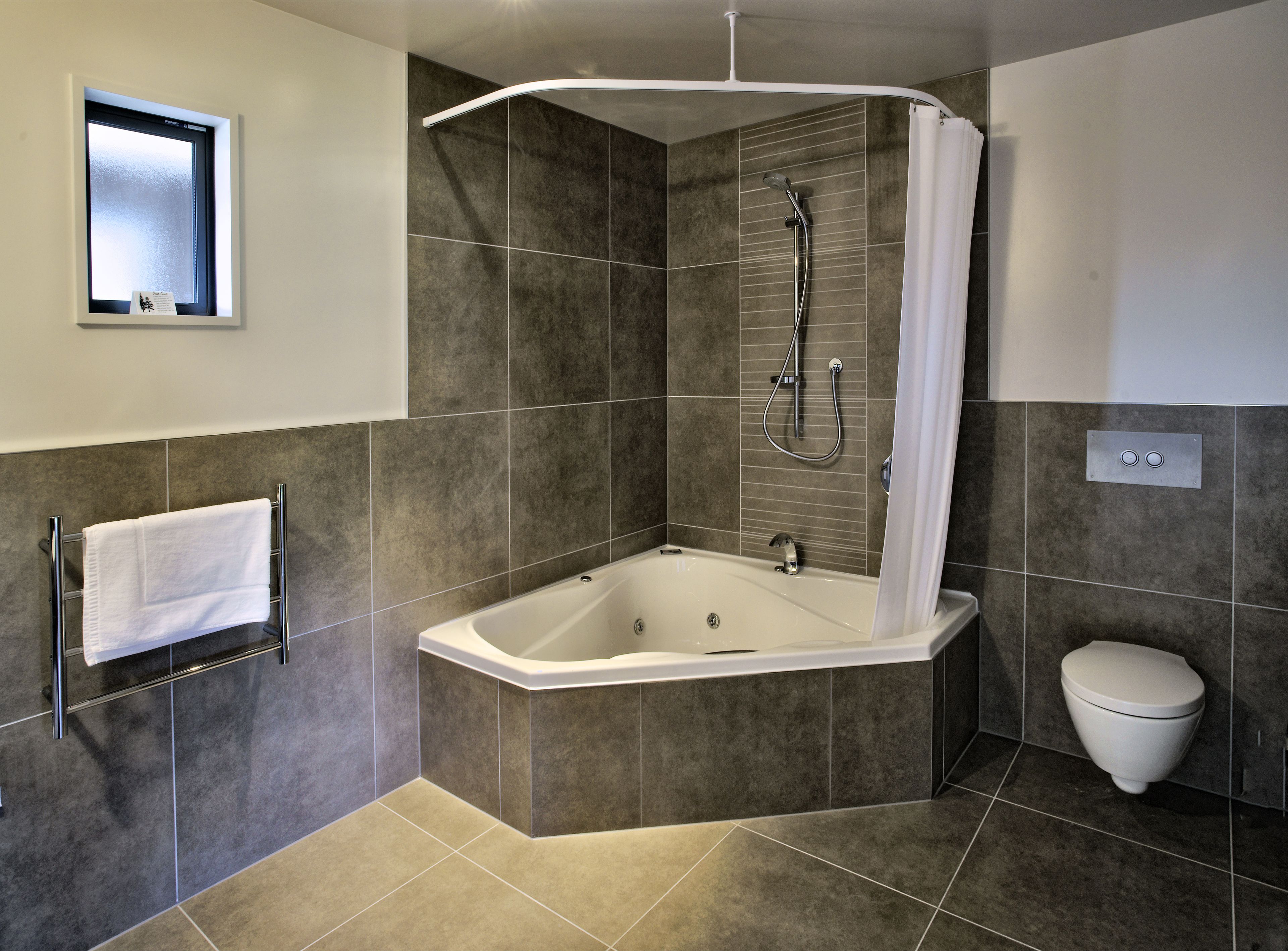 A modern bathroom with a freestanding bathtub, a shower with a curved glass enclosure, and a toilet.